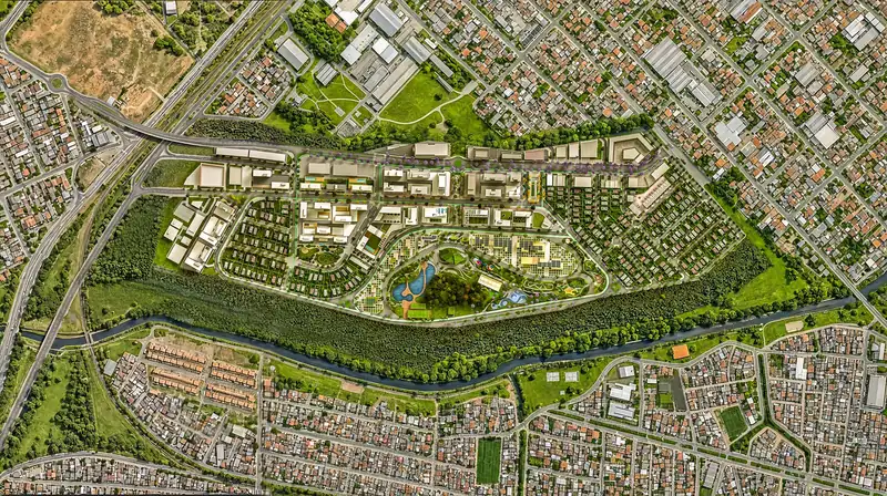 Vista de satélite de um bairro planejado entre um rio arborizado e avenidas, com quadras de edifícios, parque central com lago e a malha de casas da cidade ao redor.