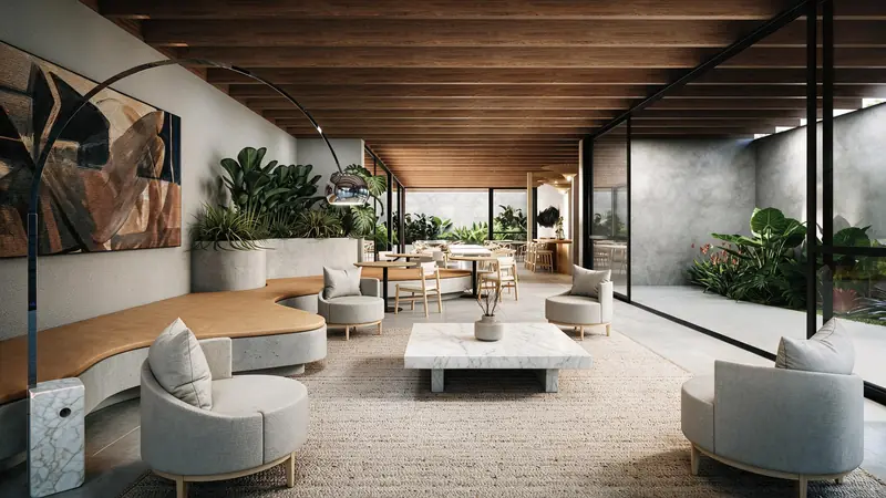 Lounge com forro de vigas de madeira, banco curvo estofado, poltronas cinza, mesa de mármore sobre tapete de fibra e parede de vidro voltada ao jardim.